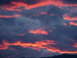 2006 Ford E350 - Dramatic sunset clouds paint the sky with vibrant hues of orange and pink over a dark horizon.