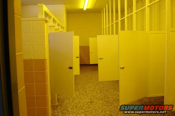 Interior of a public restroom with yellow stalls and tiled floor