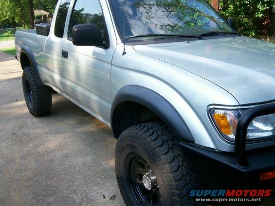 Silver Toyota pickup truck with black fender flares and off-road tires. Bull bar visible on front