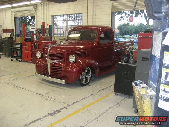 Red pickup truck with chrome wheels in a garage