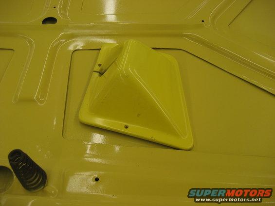 Yellow painted metal surface with a yellow plastic vent and a black spring