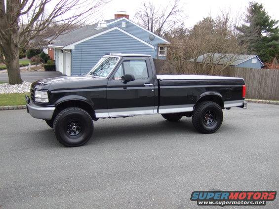 Black 1992 Ford F-150 pickup truck with silver trim and a tonneau cover, parked on asphalt