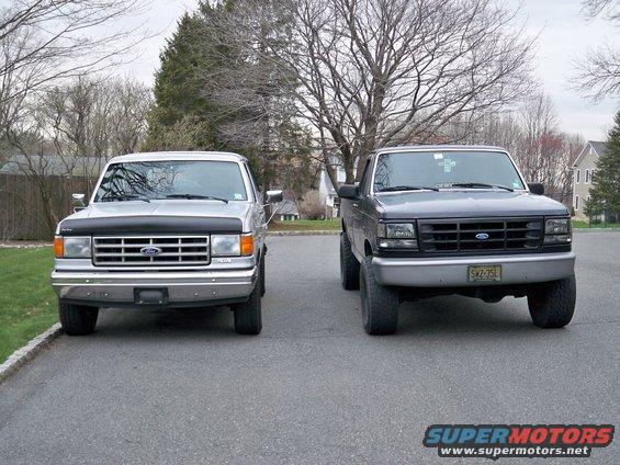 Two Ford F-150 trucks parked side-by-side, one silver, one dark gray, both facing forward
