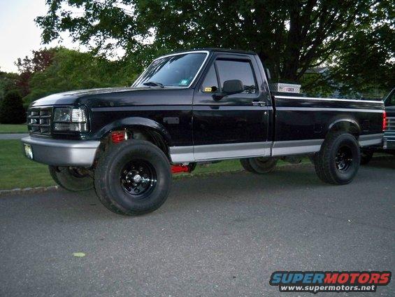 Black 1995 Ford F-150 pickup truck, lifted with aftermarket wheels, parked on asphalt