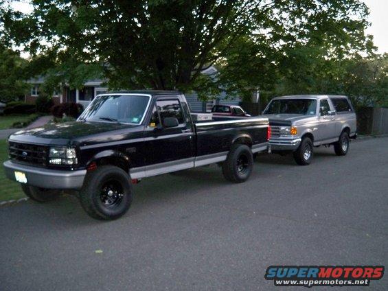 Black Ford F-150 pickup truck towing a silver Ford Bronco