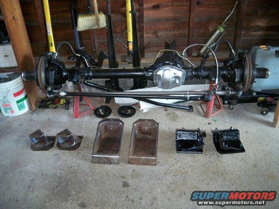 Differential axle assembly on jack stands with various metal parts on the floor
