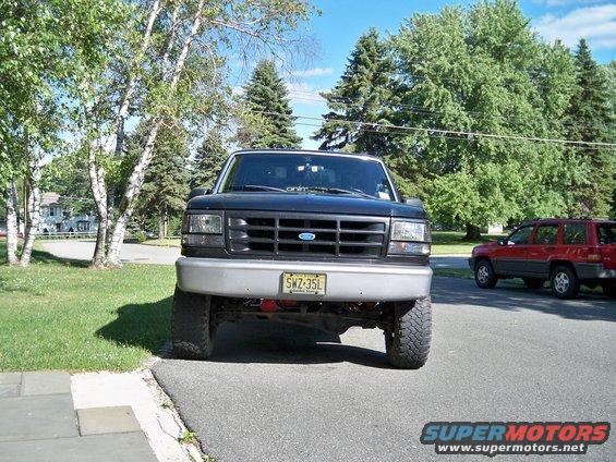 1995 Ford F-150 front view, lifted with aftermarket wheels. Red Jeep Grand Cherokee parked to the right