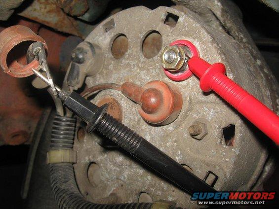 Alternator with red and black test leads attached to terminals