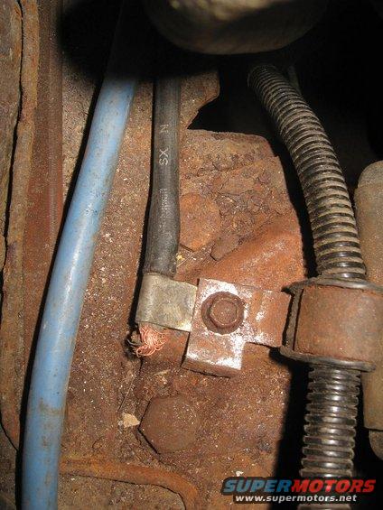 Close-up of engine bay wiring and rusted metal components