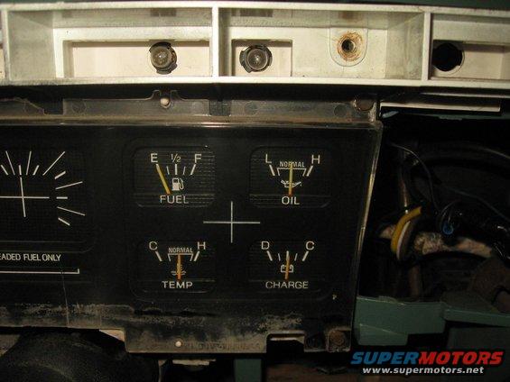 Close-up of a vehicle's dashboard gauges, showing fuel, oil, temperature, and charge indicators