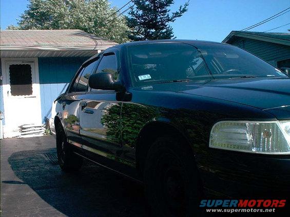Black 2000 Ford Crown Victoria parked in driveway, front passenger side visible, with a house in the background