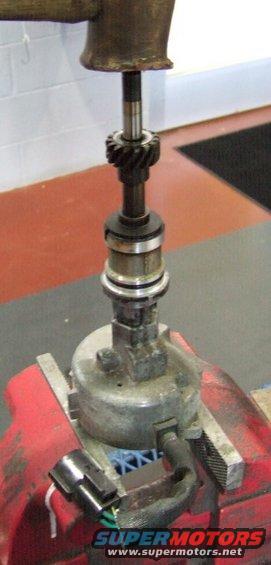 Distributor assembly held in a red vise with a gear on top shaft