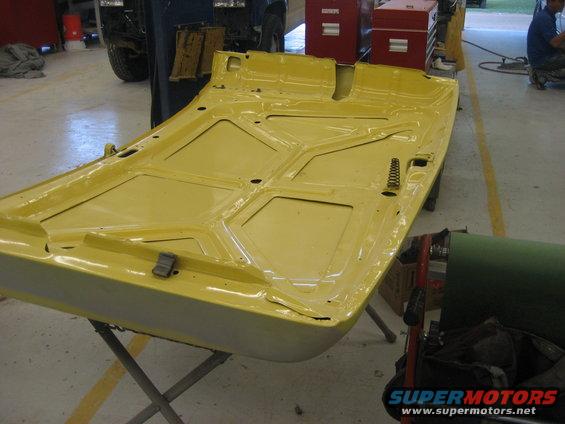 Underside of a yellow car hood on a stand
