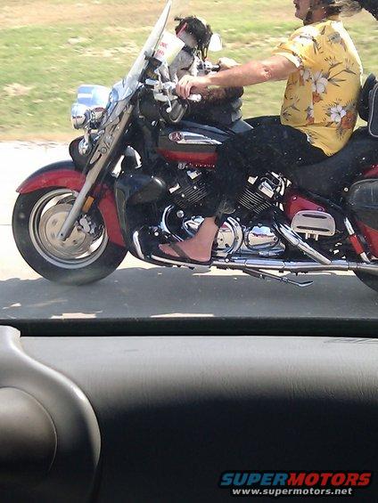 Red and black motorcycle with a rider wearing a yellow floral shirt and flip-flops