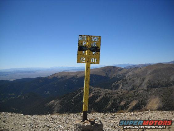 Sign at Red Cone Peak with elevation 12,010 feet. Mountainous landscape under a clear blue sky