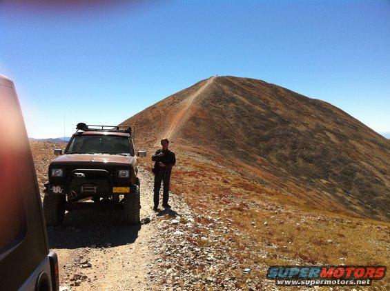 Brown 1986 Ford Bronco II with roof rack and winch parked on a mountain road