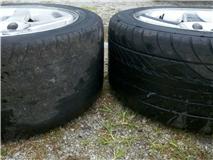 Worn tire next to a new tire on alloy wheels