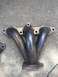 2003 Acura TL - A close-up view of an exhaust manifold, showing the junction of four pipes.