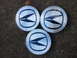 2003 Acura TL - Three silver hubcaps with a distinctive blue and black emblem are shown, with one cap exhibiting some wear.