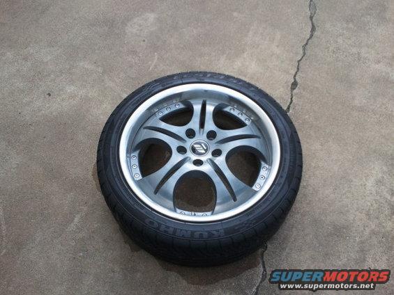 Tire and wheel assembly with a silver five-spoke rim and black tire, resting on concrete