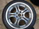 2003 Acura TL - A single silver alloy wheel with a multi-spoke design is shown, resting on a concrete surface.