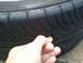 2003 Acura TL - A hand inserts a penny into the tire tread to gauge the remaining tread depth.