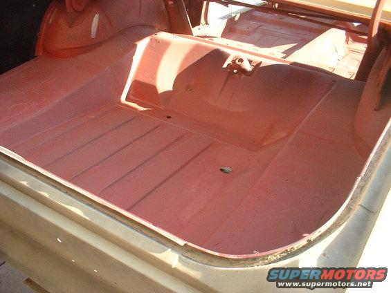 Car trunk interior with red primer, ribbed floor, and visible latches