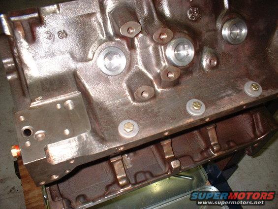 Close-up of a cast iron engine block with bolt holes and machined surfaces. "10 C" is visible cast into the metal