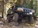 1994 Ford Bronco - Modified Ford Bronco navigates a challenging rocky terrain in a wooded area.