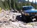 1994 Ford Bronco - A blue Ford Bronco navigates a rocky trail, with another vehicle stuck in the background.