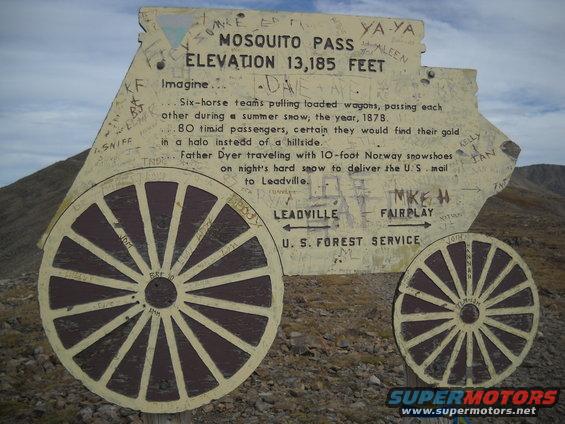 Sign shaped like a wagon with wheels, depicting historical text and graffiti, at Mosquito Pass