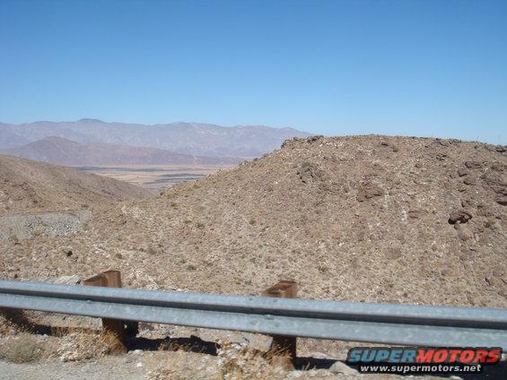 Desert landscape with mountains and a guardrail in the foreground