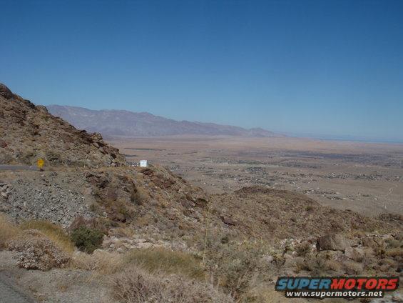 White box truck parked on a rocky mountain road overlooking a desert valley