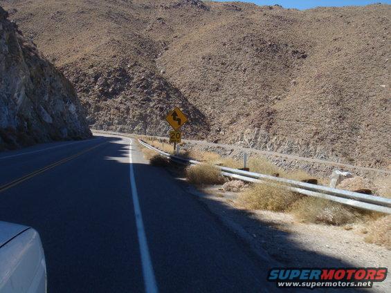View from a car on a road with a 20 mph curve warning sign on a mountainside
