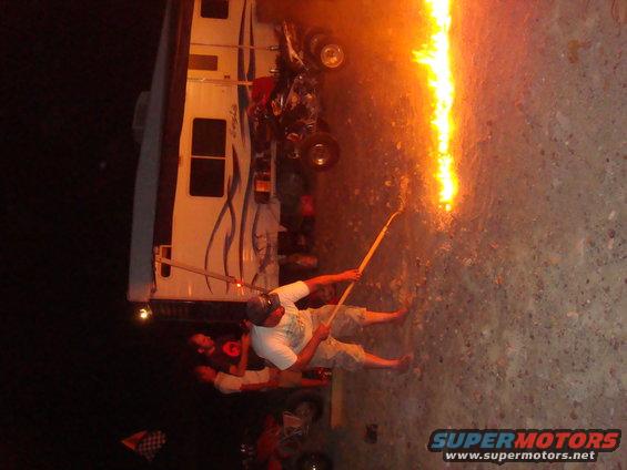 RV parked, people holding sticks with fire on them