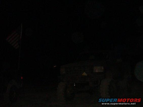 Dark truck with American flag on pole to the left