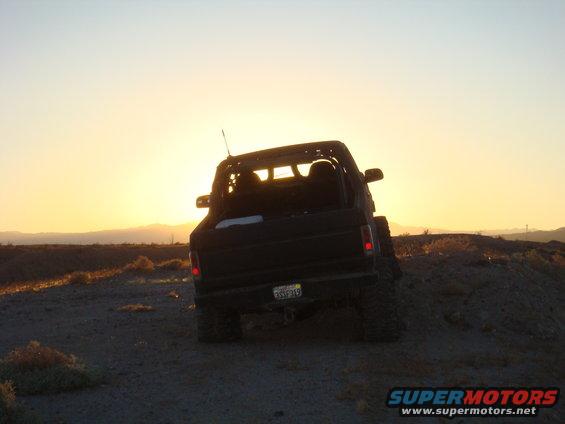 1992 Ford Bronco rear view on dirt hill with sunset