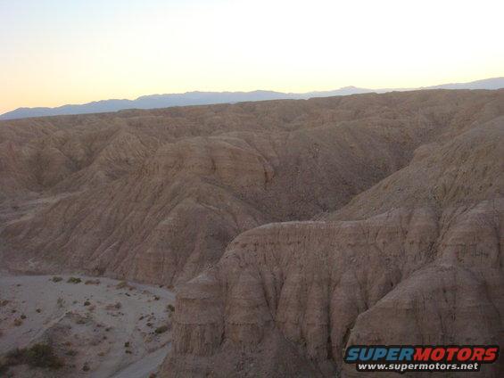 Desert landscape with eroded hills and a clear sky at sunset