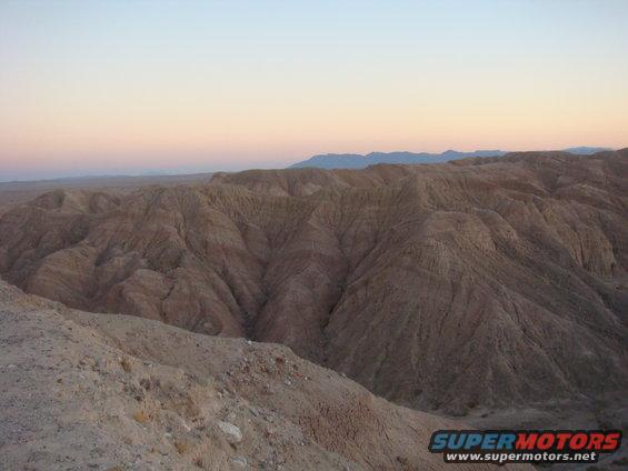 Badlands landscape with layered hills and a soft gradient sky at sunset