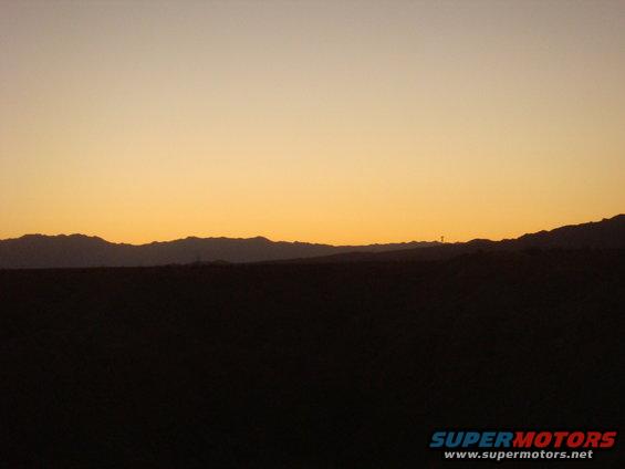 Sunset over a mountain range with a dark foreground