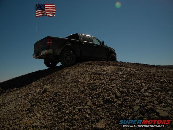 Dark pickup truck on a dirt hill with an American flag