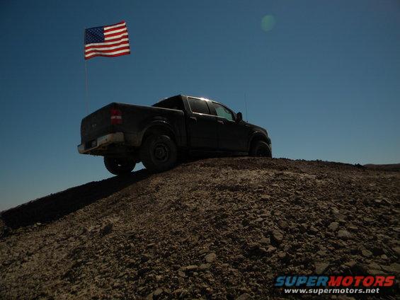Dark pickup truck on a hill with an American flag