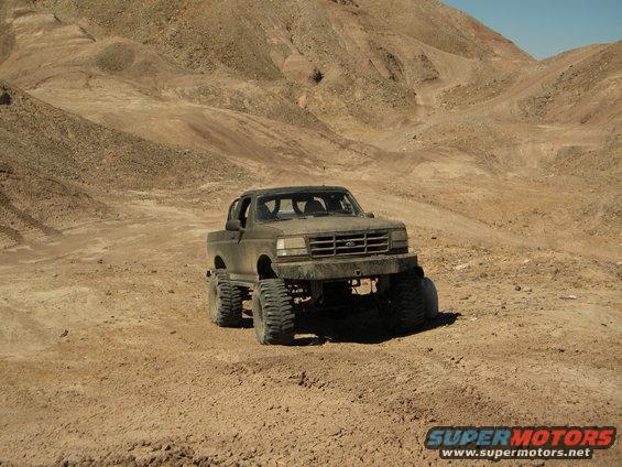1992 Ford Bronco modified with large tires and suspension, driving in a desert