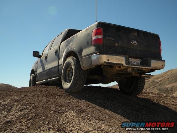 Ford F-150 pickup truck driving on dirt hill, rear view. License plate 8B25378