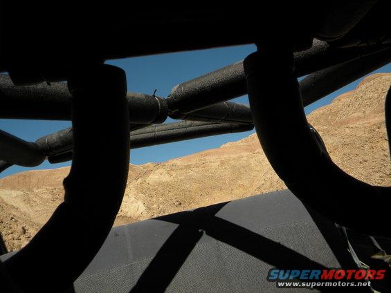 Black roll cage tubes and dark gray seat visible through a desert landscape