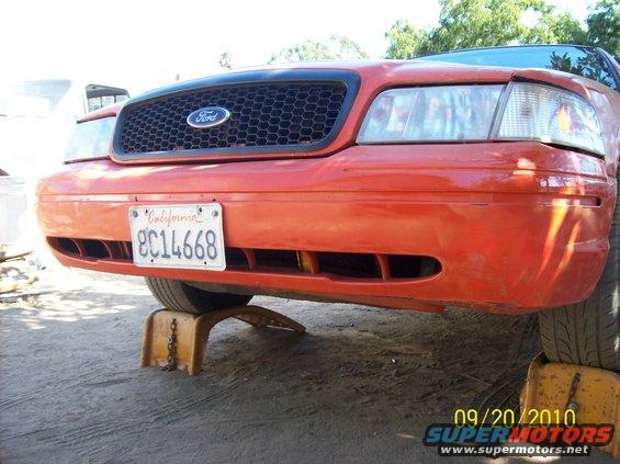 Orange 2002 Ford Crown Victoria front end on jack stands, California license plate 8C14668 visible