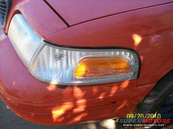 Red 2002 Ford Crown Victoria front fender and headlight assembly with cracked amber turn signal