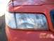 2002 Ford Crown Victoria - Close-up of the front headlight on a red 2002 Ford Crown Victoria.
