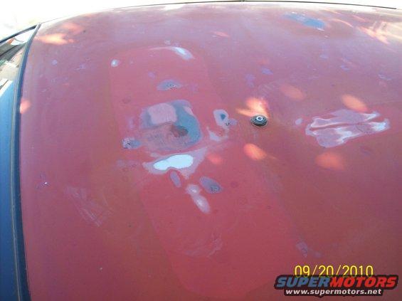 Car hood showing primer and rust spots, with a small black antenna base