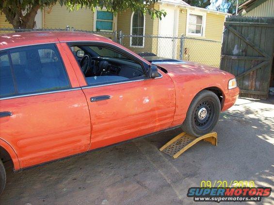 Orange 2002 Ford Crown Victoria on yellow ramps, side view. Date stamp shows 09/20/2010